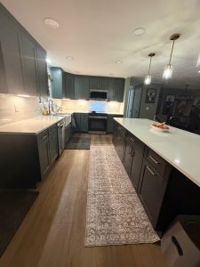 Open-concept kitchen and living room with a tiled fireplace and fresh paint by All Things Remodel